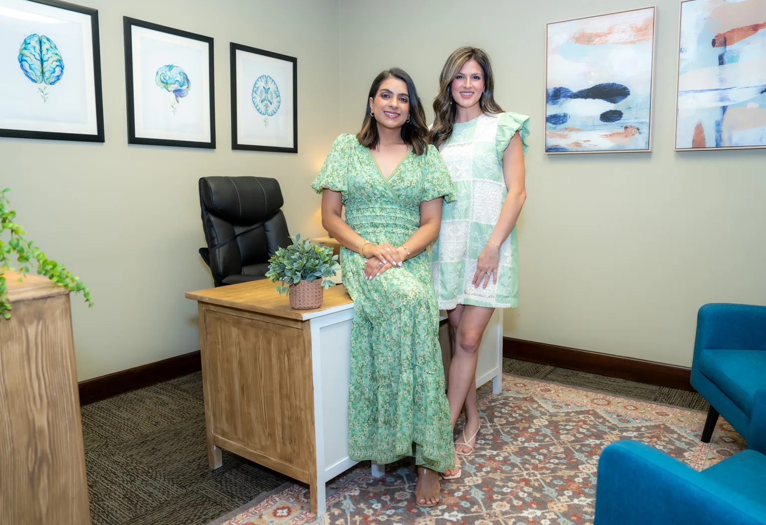 Priya Patel, PA-C and Julia Klug, PA-C in their office, with framed brain prints on the wall